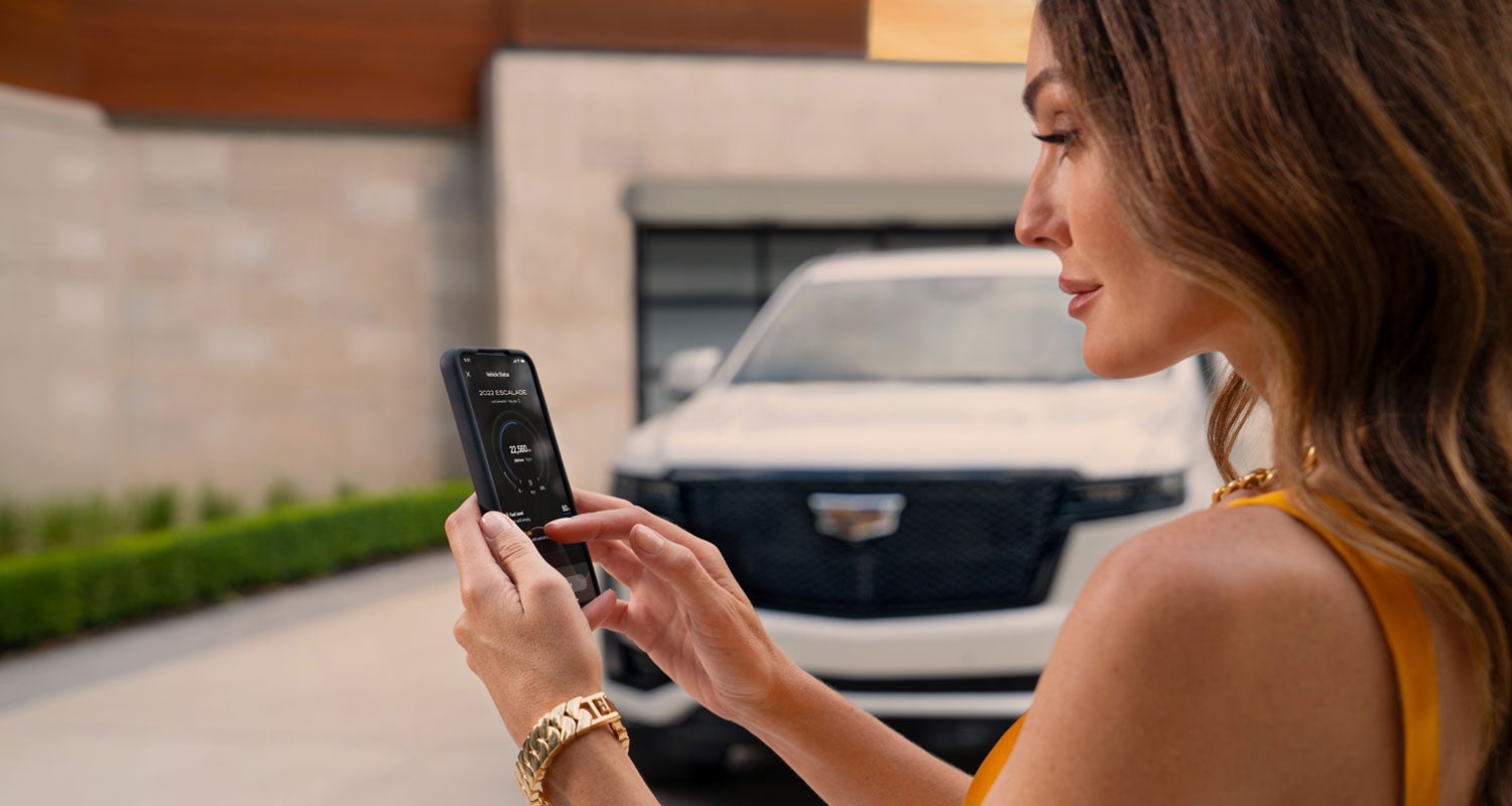 lady checking her mobile with a Cadillac vehicle background | Denny Menholt Cadillac in Rapid City SD